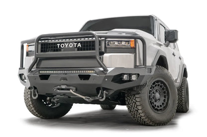 Fab Fours Matrix front bumper with full guard on a silver Toyota Land Cruiser, front three-quarter view from the driver side, showing the full grille guard, LED light bar and winch line