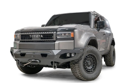 Fab Fours Matrix front bumper on a silver Toyota Land Cruiser, front three-quarter view from the driver side, showing the LED light bar, cube lights and winch fairlead