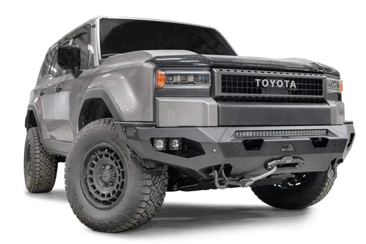 Fab Fours Matrix front bumper on a silver Toyota Land Cruiser, front three-quarter view from the passenger side, showing the LED light bar, cube lights and winch fairlead