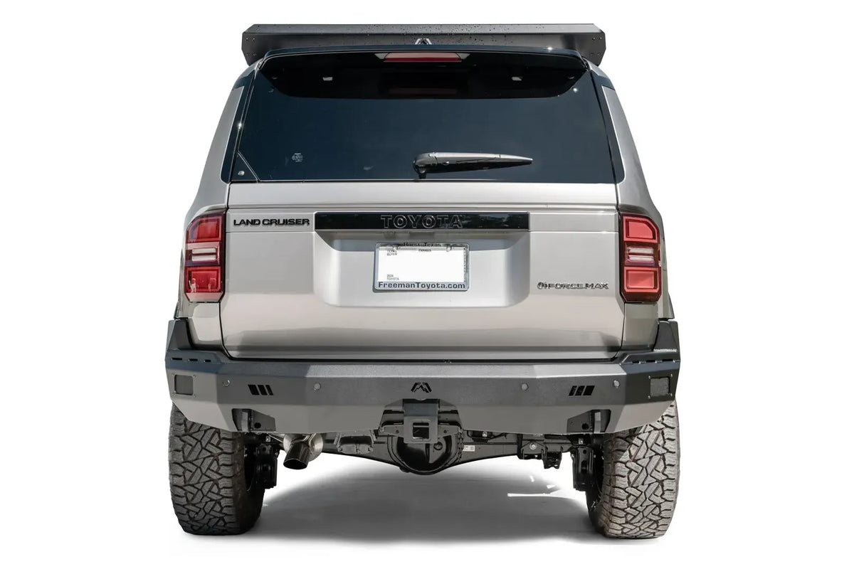 Fab Fours Premium rear bumper on a silver Toyota Land Cruiser, straight rear view, with parking sensors and center hitch receiver