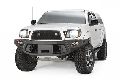 Fab Fours Premium front bumper on a white Toyota Tacoma, front view, showing the recessed winch plate, round fog lights and angled end caps
