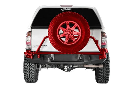 Fab Fours Premium rear bumper on a white Toyota Tacoma, straight-on rear view, showing the rear bumper, receiver hitch opening and a swing-out tire carrier highlighted in red