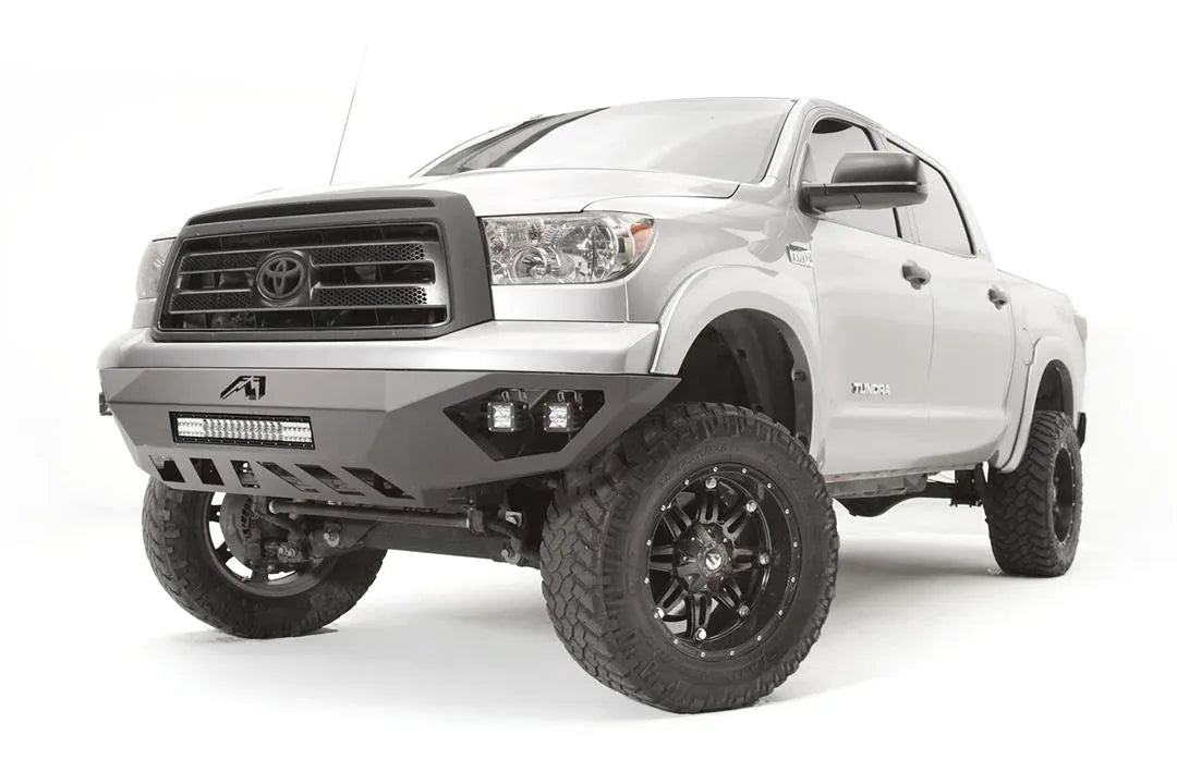 Fab Fours Vengeance front bumper on a silver Toyota Tundra, front three-quarter view from the driver side, showing the LED light bar, cube lights and skid plate