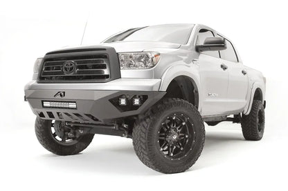 Fab Fours Vengeance front bumper on a silver Toyota Tundra, front three-quarter view from the driver side, showing the LED light bar, cube lights and skid plate