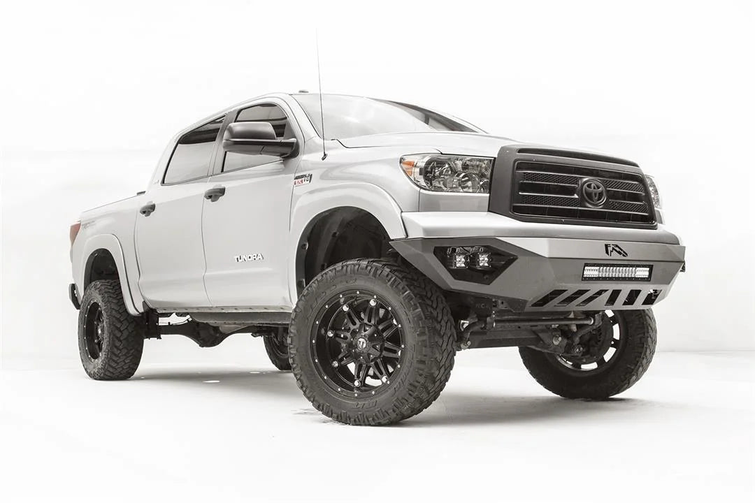 Fab Fours Vengeance front bumper on a silver Toyota Tundra, front three-quarter view from the passenger side, showing the LED light bar, cube lights and skid plate