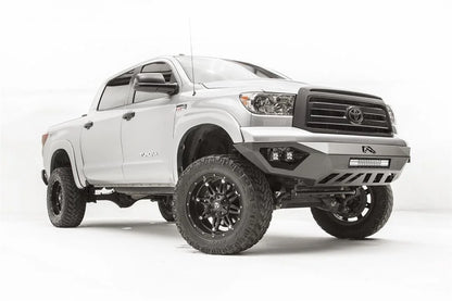Fab Fours Vengeance front bumper on a silver Toyota Tundra, front three-quarter view from the passenger side, showing the LED light bar, cube lights and skid plate