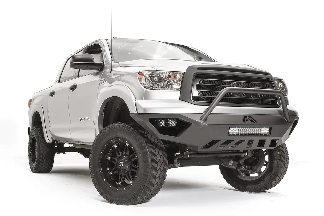 Fab Fours Vengeance front bumper with pre-runner guard on a silver Toyota Tundra, front three-quarter view from the passenger side, showing the pre-runner hoop, the LED light bar, cube lights and skid plate