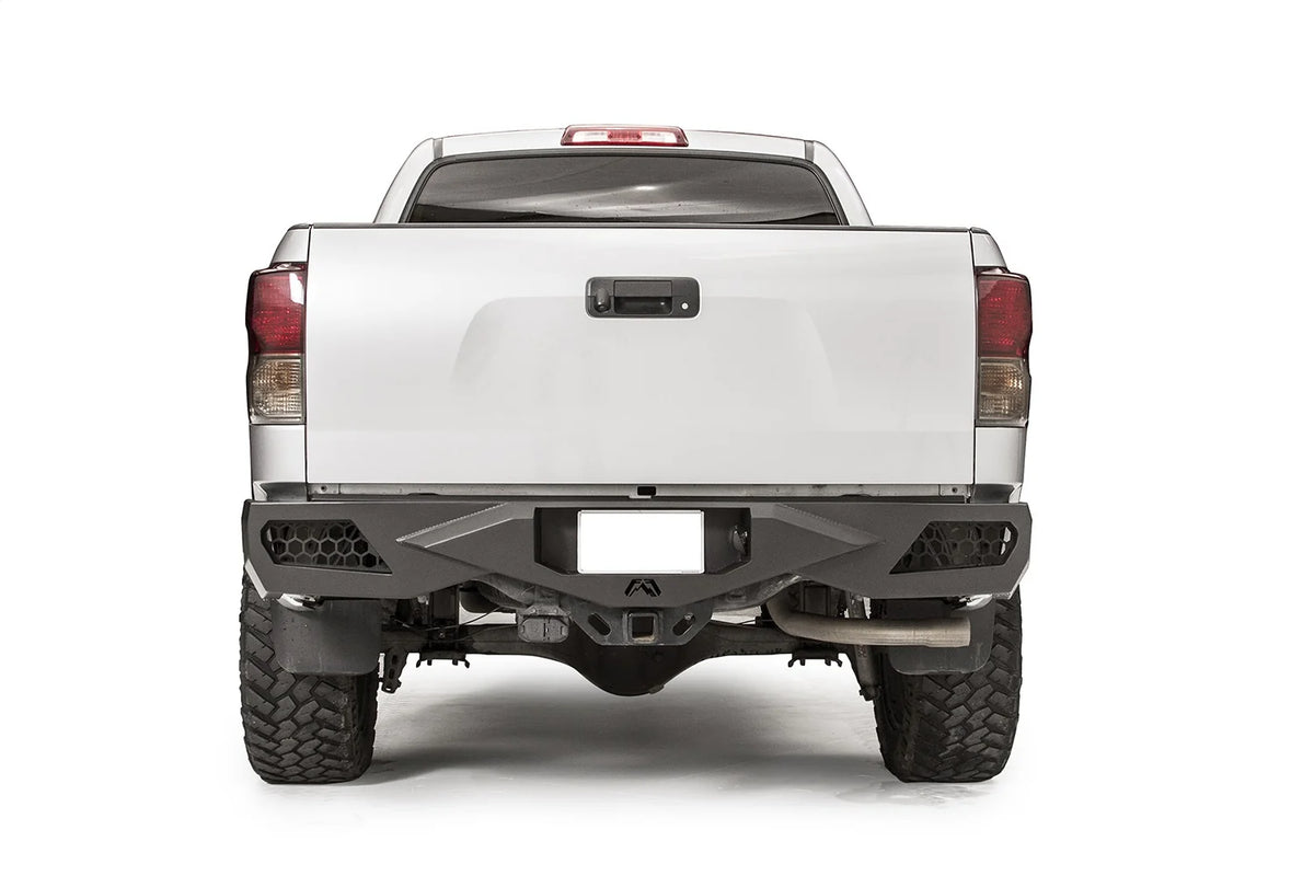 Fab Fours Vengeance rear bumper on a silver Toyota Tundra, straight-on rear view, showing the honeycomb light cutouts, centre plate recess and receiver hitch