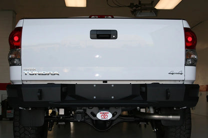 Fab Fours Premium rear bumper on a white Toyota Tundra, straight-on rear view in a garage, showing the full-width bumper face, end caps and receiver hitch