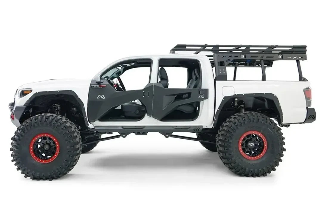Fab Fours trail doors on a lifted white Toyota Tacoma, driver-side profile view, showing the black faceted front and rear doors, with Fab Fours fenders, rock sliders and an overland bed rack