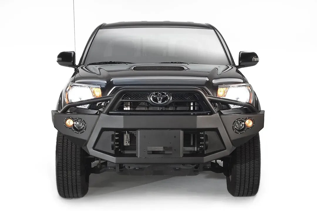 Fab Fours Premium front bumper with pre-runner guard on a black Toyota Tacoma, front view, showing the pre-runner hoop, recessed winch plate and round fog lights