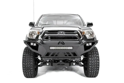 Fab Fours Vengeance front bumper with high pre-runner guard on a gray Toyota Tacoma, front view, showing the high pre-runner hoop, LED light bar, cube lights and skid plate