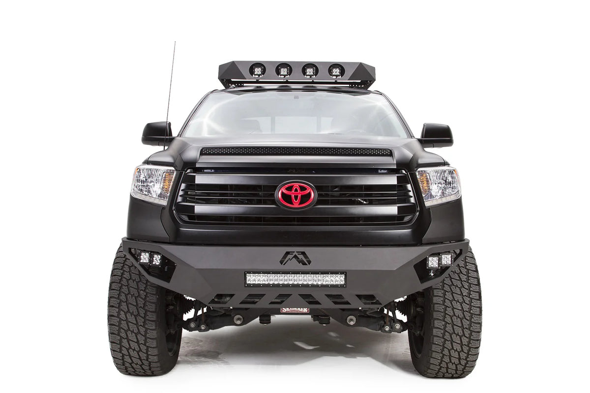Fab Fours Vengeance front bumper on a matte black Toyota Tundra, front view, showing the LED light bar, cube lights and skid plate