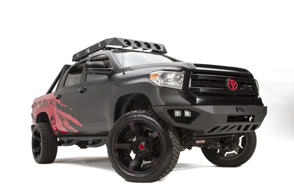 Fab Fours Vengeance front bumper on a matte black Toyota Tundra, front three-quarter view from the passenger side, showing the LED cube lights, angled end caps and skid plate