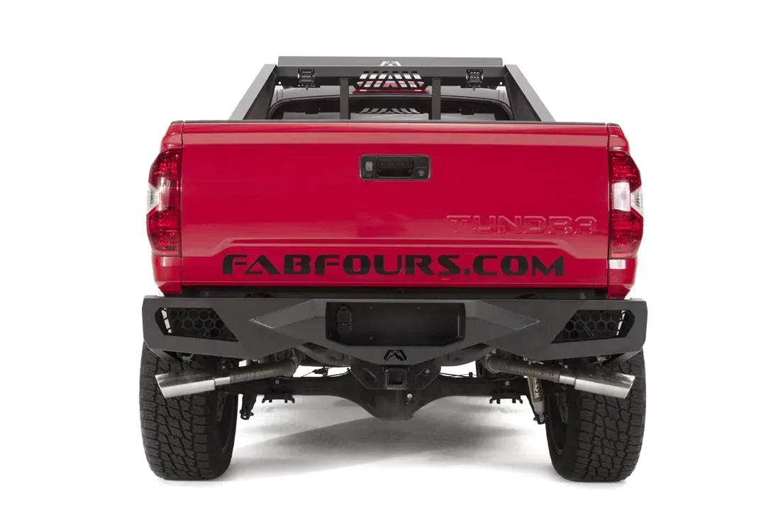 Fab Fours Vengeance rear bumper on a red and black Toyota Tundra, straight-on rear view, showing the full bumper width, integrated light pods, and center hitch opening