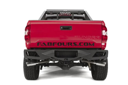 Fab Fours Vengeance rear bumper on a red and black Toyota Tundra, straight-on rear view, showing the full bumper width, integrated light pods, and center hitch opening