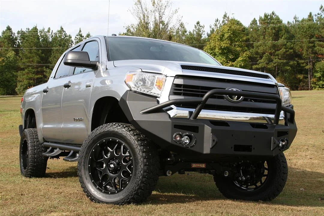 Fab Fours Premium front bumper with pre-runner guard on a silver Toyota Tundra, front three-quarter view outdoors, showing the pre-runner hoop, round fog lights, and winch-ready center section