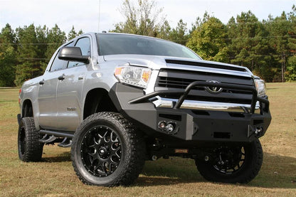Fab Fours Premium front bumper with pre-runner guard on a silver Toyota Tundra, front three-quarter view outdoors, showing the pre-runner hoop, round fog lights, and winch-ready center section