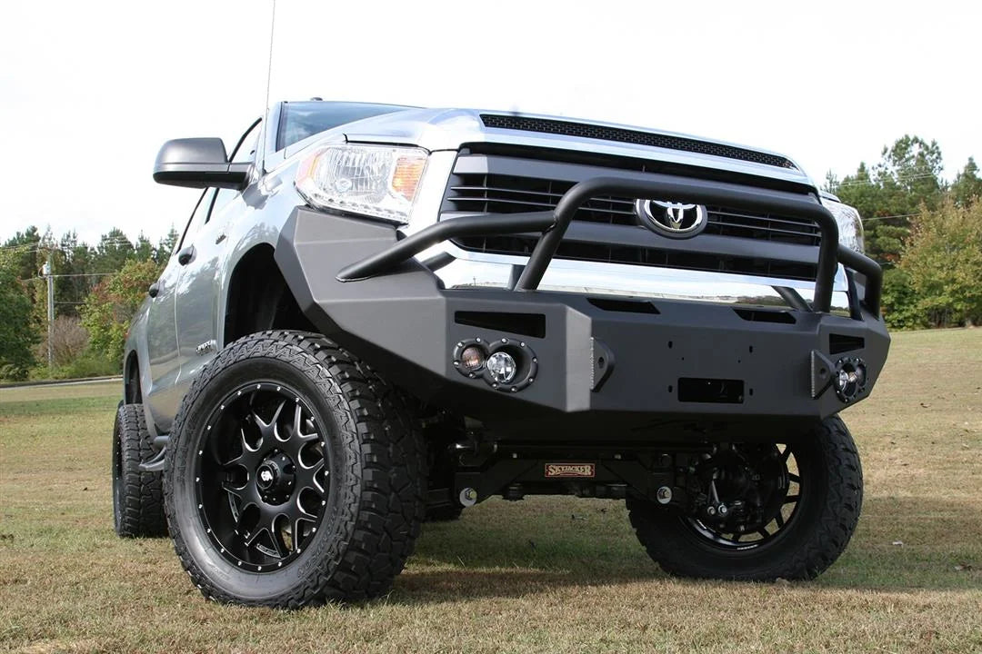 Fab Fours Premium front bumper with pre-runner guard on a silver Toyota Tundra, front three-quarter view outdoors, showing the pre-runner hoop, fog light pods, and winch opening