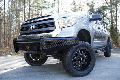 Fab Fours Black Steel front bumper on a silver Toyota Tundra, low front three-quarter view outdoors, showing the diamond-plate face, wraparound end cap, and tubular top bar