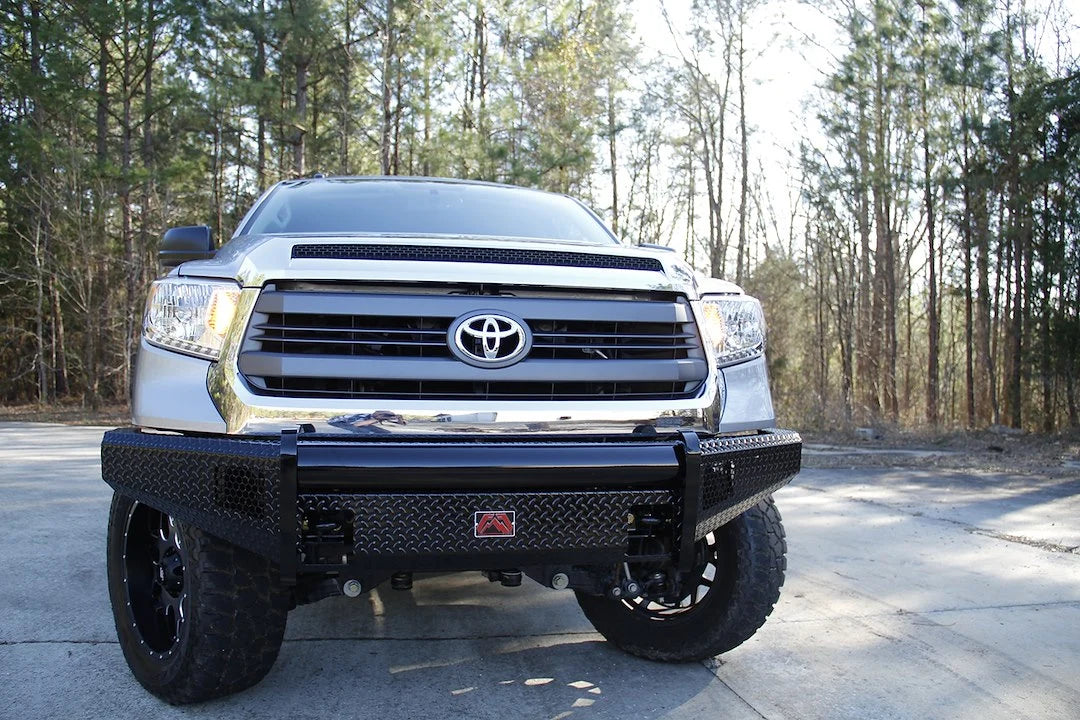 Fab Fours Black Steel front bumper on a silver Toyota Tundra, straight-on front view outdoors, showing the no-guard design, diamond-plate face, and tubular top bar