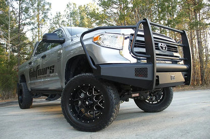 Fab Fours Black Steel Elite front bumper with full guard on a silver Toyota Tundra, low front three-quarter view outdoors, showing the full grille guard, headlight hoop, and mesh light opening