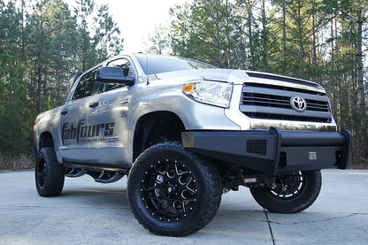 Fab Fours Black Steel Elite front bumper on a silver Toyota Tundra, low front three-quarter view outdoors, showing the no-guard design, mesh light openings, and wraparound end caps