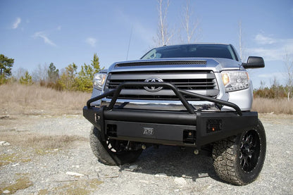 Fab Fours Black Steel Elite front bumper with pre-runner guard on a silver Toyota Tundra, front view outdoors, showing the pre-runner hoop, Elite badge, and mesh light openings