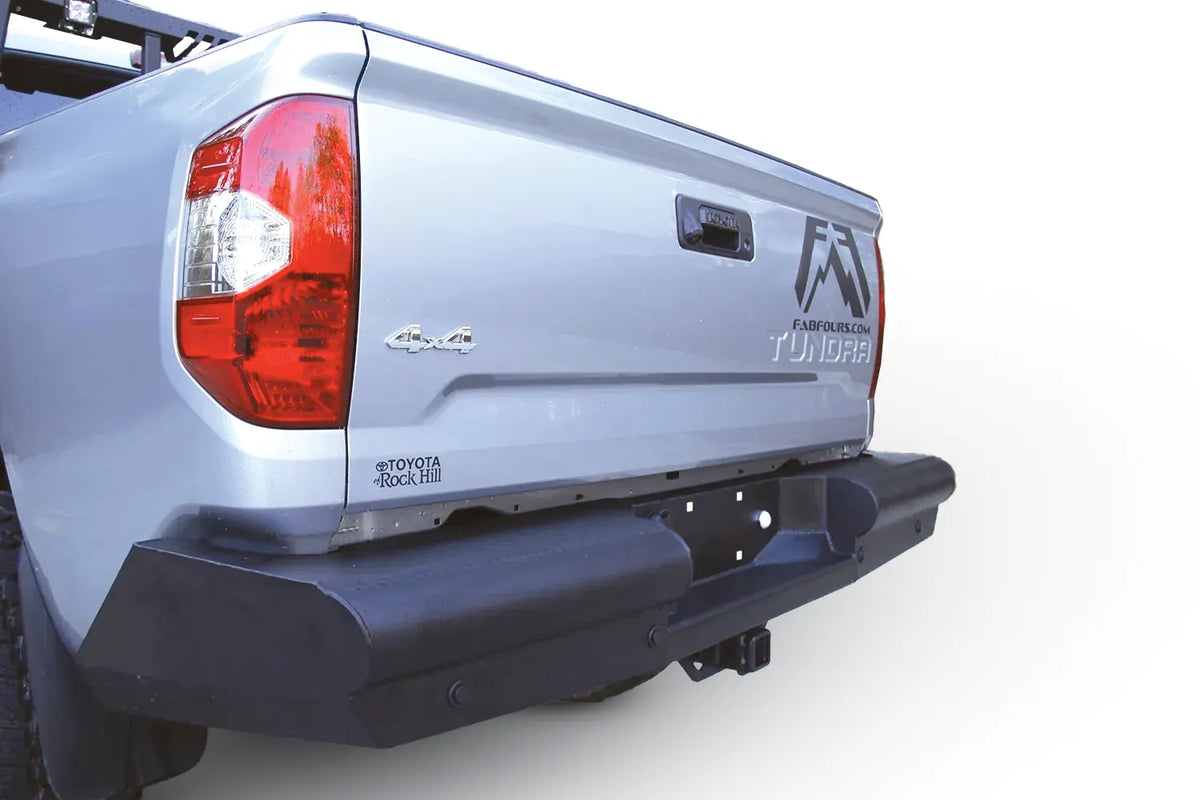 Fab Fours Black Steel Elite rear bumper on a silver Toyota Tundra, close rear three-quarter view outdoors, showing the smooth steel face, angled end cap, and plate mount area