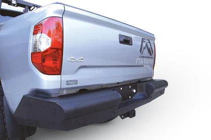 Fab Fours Black Steel Elite rear bumper on a silver Toyota Tundra, close rear three-quarter view outdoors, showing the smooth steel face, angled end cap, and plate mount area