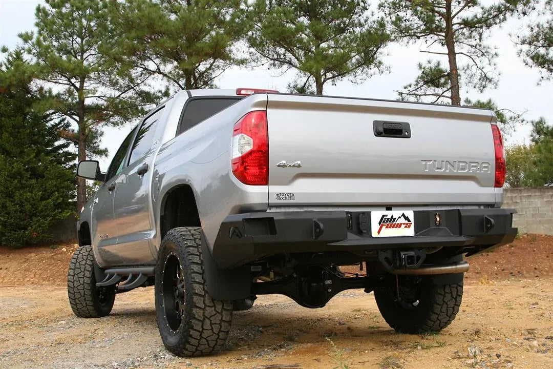 Fab Fours Premium rear bumper on a silver Toyota Tundra, rear three-quarter view outdoors, showing the recessed light pods, center plate mount, and wraparound end caps