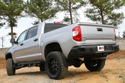 Fab Fours Premium rear bumper on a silver Toyota Tundra, rear three-quarter view outdoors, showing the recessed light pods, angled end caps, and plate mount