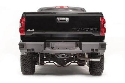 Fab Fours Premium rear bumper on a black Toyota Tundra, straight-on rear view, showing the full bumper width, center plate mount, and receiver hitch