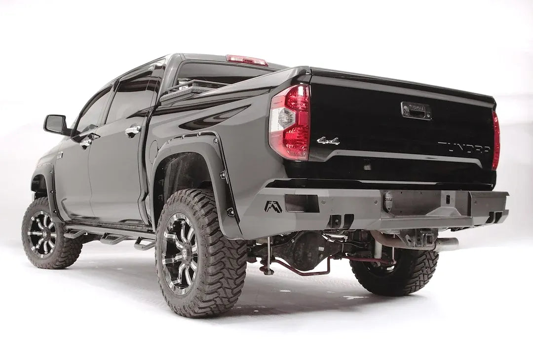 Fab Fours Premium rear bumper on a black Toyota Tundra, rear three-quarter view, showing the sensor-ready face, angled end caps, and receiver hitch
