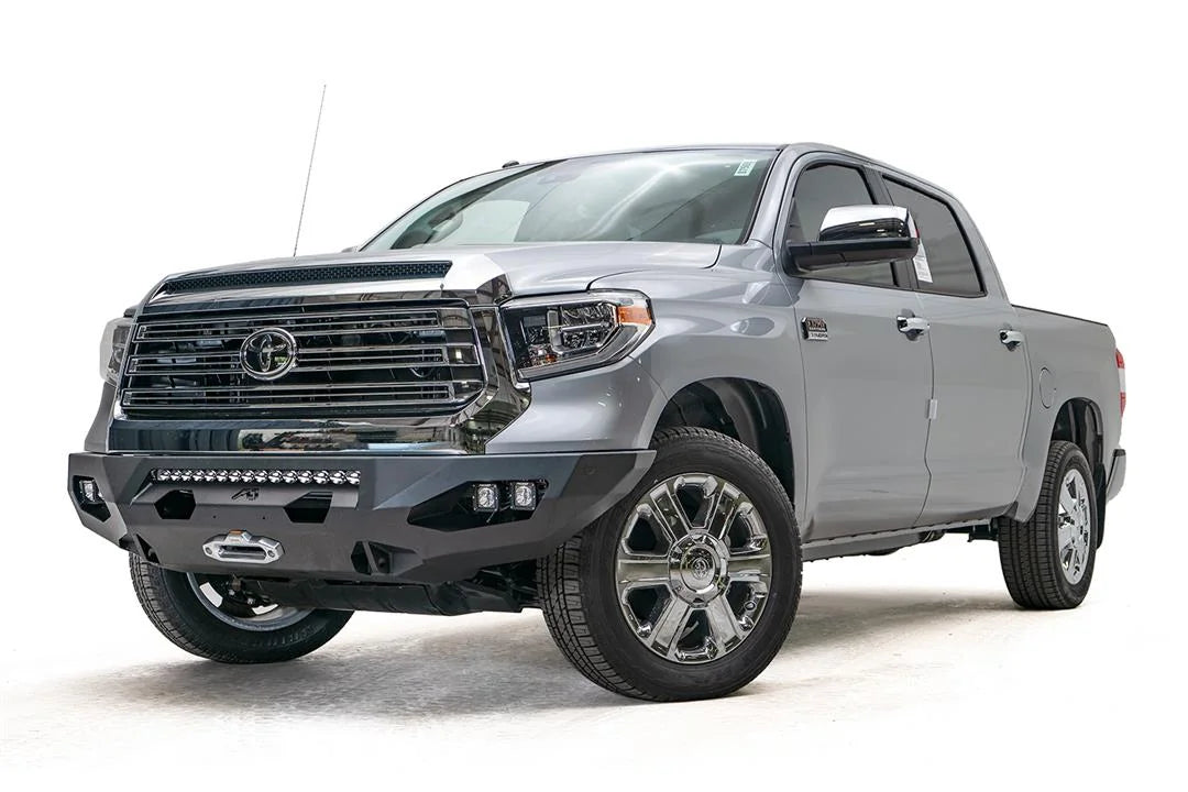 Fab Fours Matrix front bumper on a gray Toyota Tundra, front three-quarter view, showing the winch mount, LED light bar opening, and cube light pods