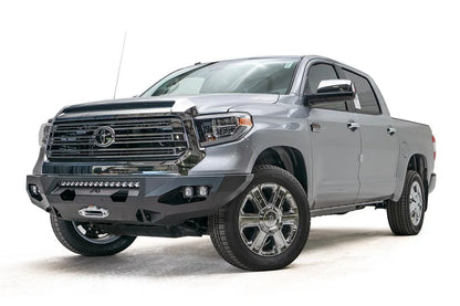Fab Fours Matrix front bumper on a gray Toyota Tundra, front three-quarter view, showing the winch mount, LED light bar opening, and cube light pods