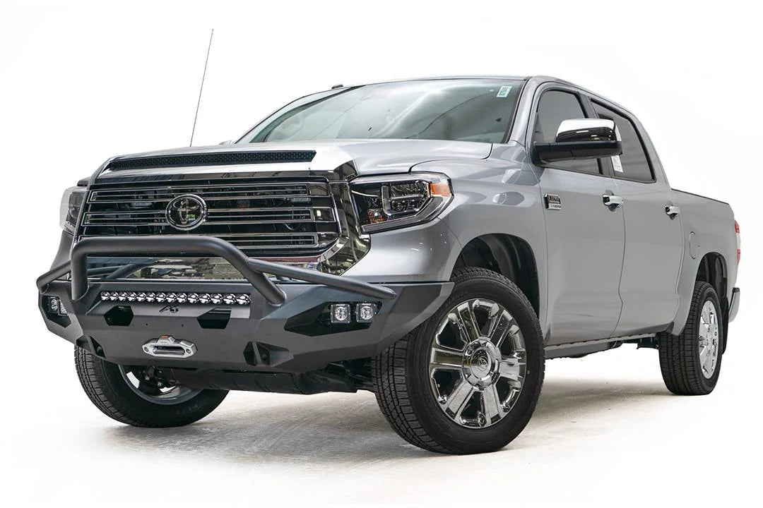 Fab Fours Matrix front bumper with pre-runner guard on a gray Toyota Tundra, front three-quarter view, showing the pre-runner hoop, LED light bar, and winch mount