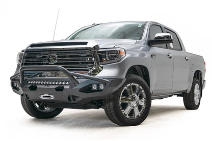 Fab Fours Matrix front bumper with pre-runner guard on a gray Toyota Tundra, front three-quarter view, showing the pre-runner hoop, LED light bar, and winch mount