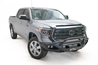 Fab Fours Matrix front bumper with pre-runner guard on a gray Toyota Tundra, front three-quarter view, showing the pre-runner hoop, light bar, and cube light pods