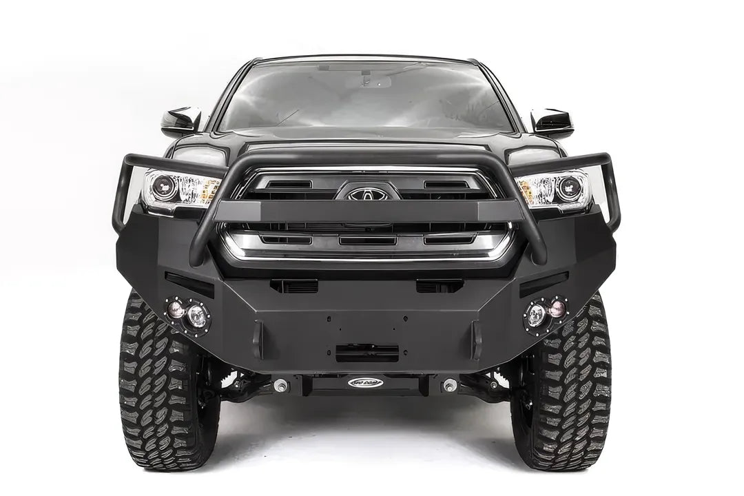 Fab Fours Premium front bumper with pre-runner guard on a dark gray Toyota Tacoma, straight-on front view, showing the guard hoop, round fog lights, and winch mount plate