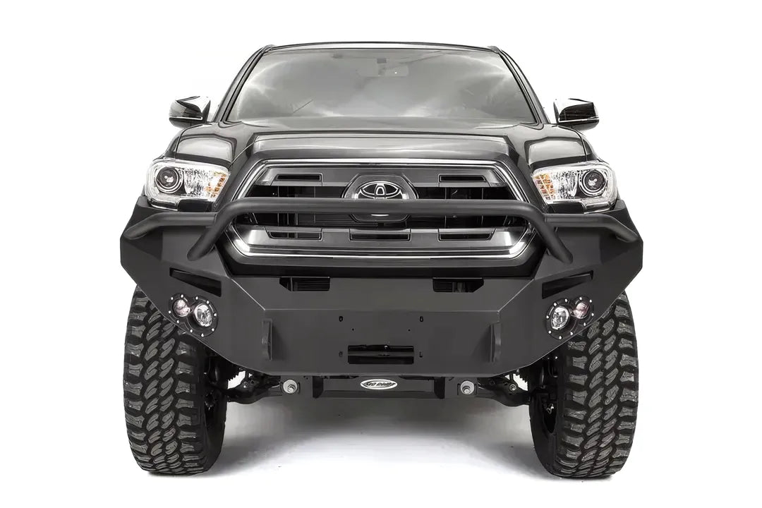 Fab Fours Premium front bumper with pre-runner guard on a dark gray Toyota Tacoma, straight-on front view, showing the pre-runner hoop, round fog lights, and winch mount plate