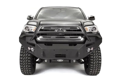 Fab Fours Premium front bumper with pre-runner guard on a dark gray Toyota Tacoma, straight-on front view, showing the pre-runner hoop, round fog lights, and winch mount plate