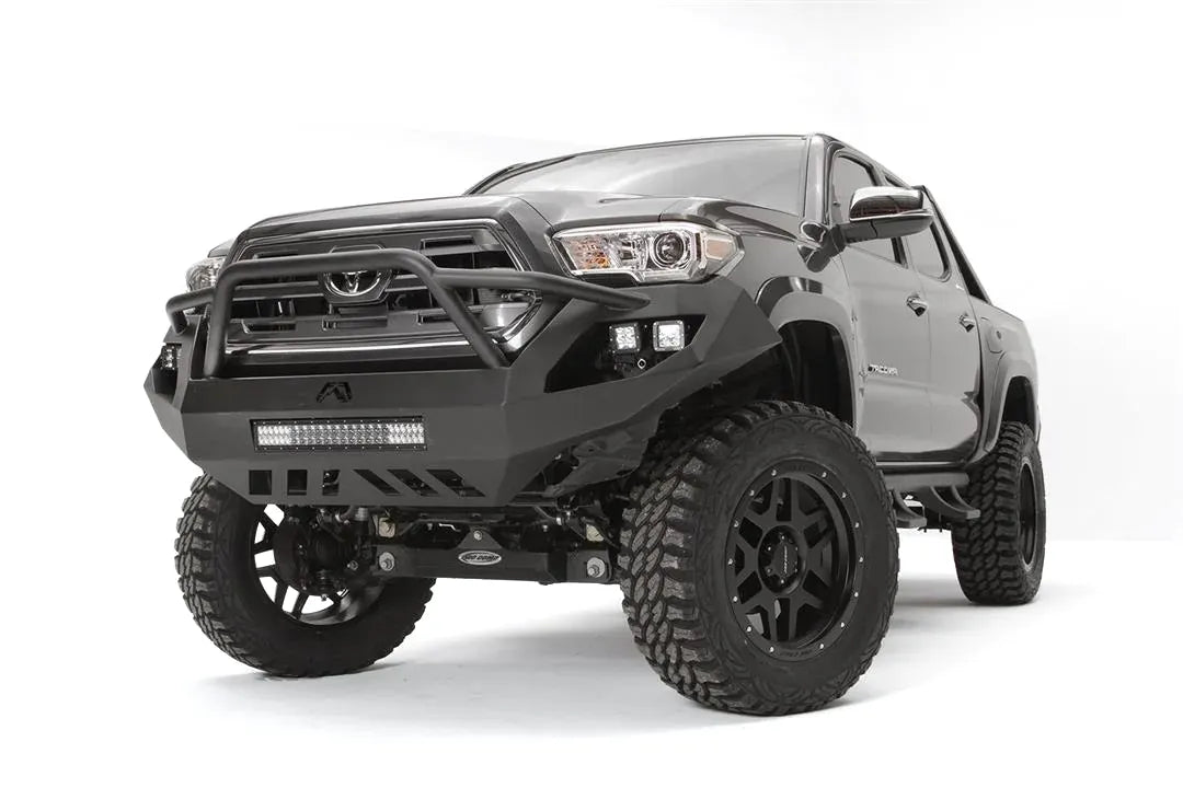 Fab Fours Vengeance front bumper with high pre-runner guard on a dark gray Toyota Tacoma, front three-quarter view, showing the pre-runner hoop, LED light bar, and skid plate