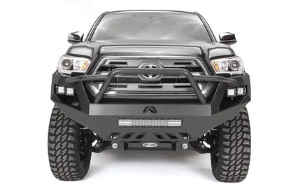 Fab Fours Vengeance front bumper with high pre-runner guard on a dark gray Toyota Tacoma, straight-on front view, showing the pre-runner hoop, LED light bar, and cube light pods