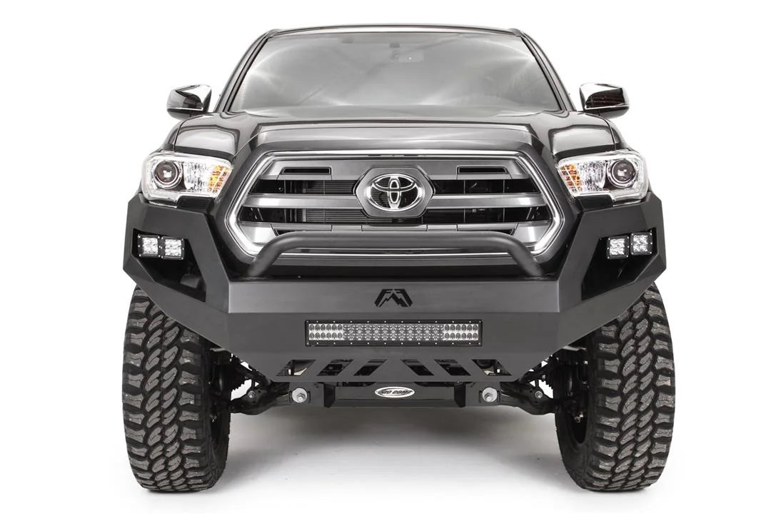 Fab Fours Vengeance front bumper with low pre-runner guard on a dark gray Toyota Tacoma, straight-on front view, showing the low guard hoop, LED light bar, and cube light pods