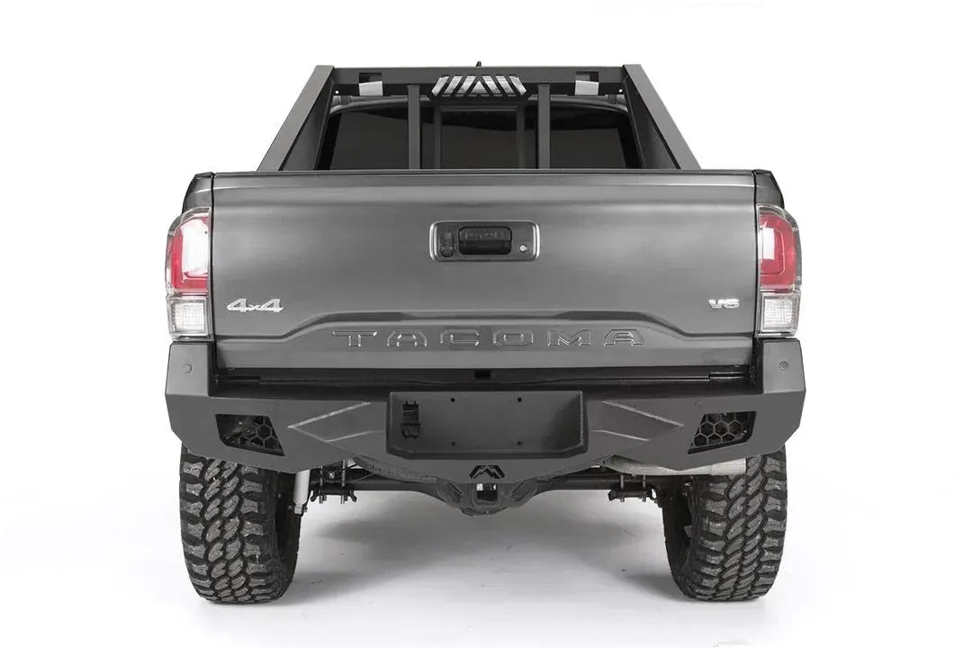 Fab Fours Vengeance rear bumper on a dark gray Toyota Tacoma, straight-on rear view, showing the full bumper width, recessed light pods, and center plate mount