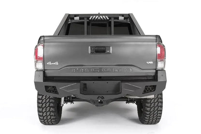 Fab Fours Vengeance rear bumper on a dark gray Toyota Tacoma, straight-on rear view, showing the full bumper width, recessed light pods, and center plate mount