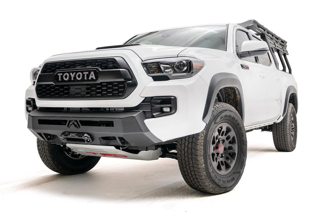 Fab Fours Hidden Winch Mount on a white Toyota Tacoma, front three-quarter view, showing the low-profile winch plate, hidden winch fairlead, and factory-style bumper fit
