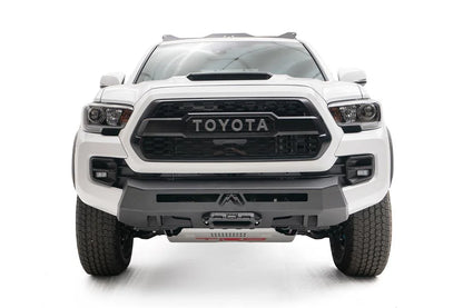 Fab Fours Hidden Winch Mount on a white Toyota Tacoma, straight-on front view, showing the low-profile winch plate, center fairlead, and no-guard design