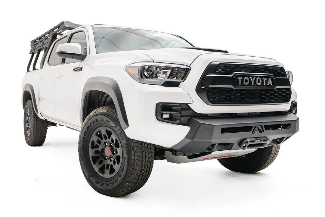Fab Fours Hidden Winch Mount on a white Toyota Tacoma, front three-quarter view, showing the low-profile winch plate, fairlead, and integrated skid area